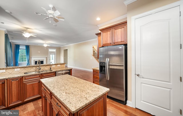 kitchen with crown molding, appliances with stainless steel finishes, a center island, and light hardwood / wood-style flooring