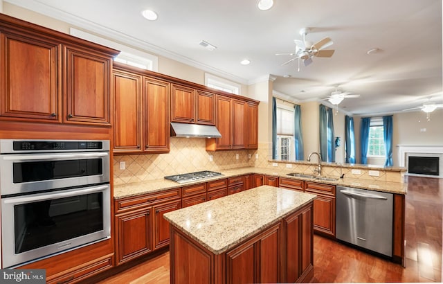 kitchen featuring sink, crown molding, stainless steel appliances, tasteful backsplash, and wood-type flooring