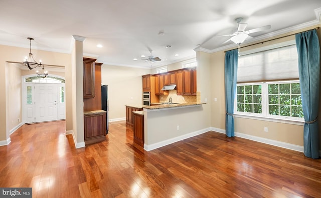 kitchen with tasteful backsplash, crown molding, dark hardwood / wood-style floors, and kitchen peninsula