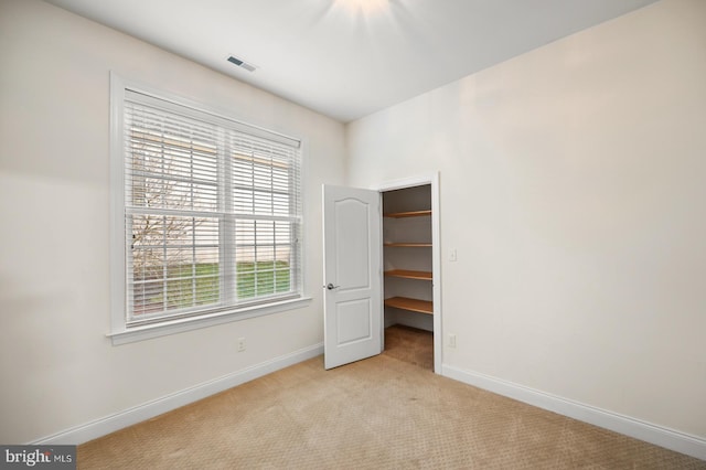 unfurnished bedroom featuring a spacious closet, light colored carpet, and a closet