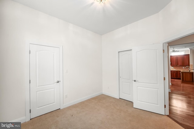 unfurnished bedroom featuring a closet, sink, and light carpet