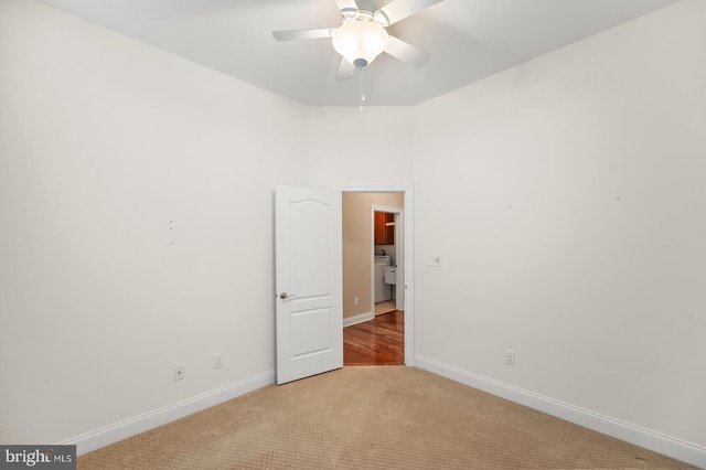 spare room with light carpet, washer / dryer, and ceiling fan