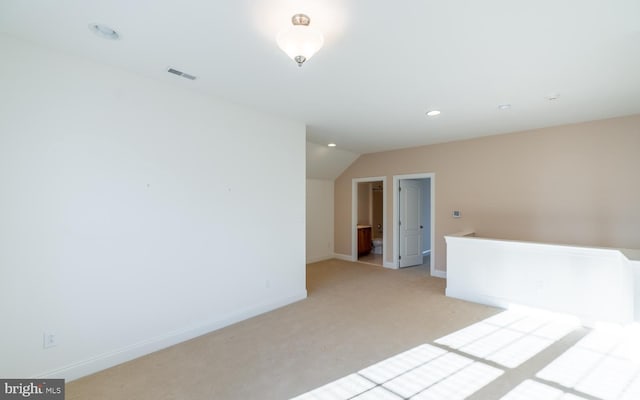 empty room featuring light colored carpet and vaulted ceiling