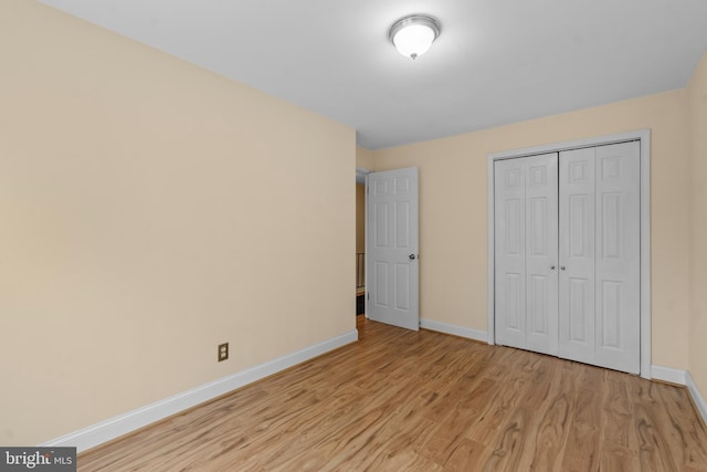 unfurnished bedroom with light hardwood / wood-style flooring and a closet