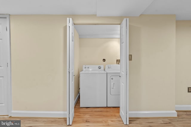 clothes washing area featuring washing machine and clothes dryer and light hardwood / wood-style floors