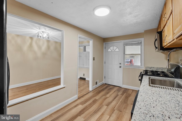 kitchen with sink, light hardwood / wood-style floors, a textured ceiling, and light brown cabinets