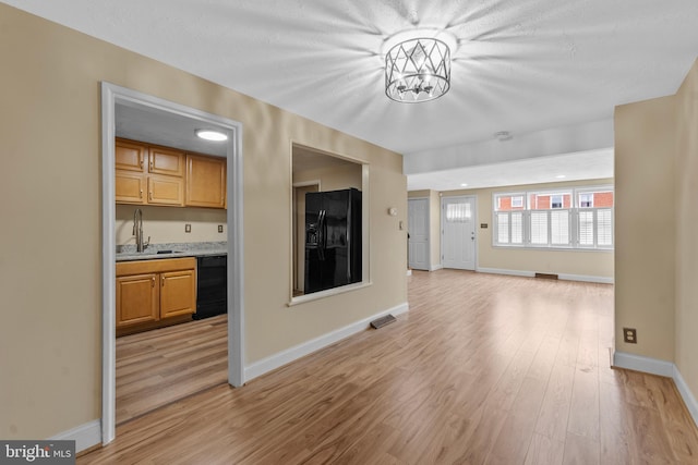 unfurnished living room featuring sink and light hardwood / wood-style flooring