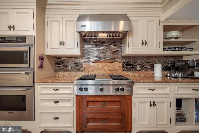 kitchen featuring white cabinetry, backsplash, appliances with stainless steel finishes, and wall chimney range hood