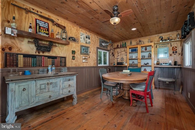 dining area featuring wooden ceiling, hardwood / wood-style flooring, wooden walls, and ceiling fan