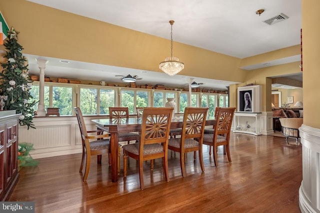 dining space with ornate columns, dark hardwood / wood-style flooring, a wealth of natural light, and ceiling fan with notable chandelier