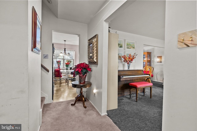 hall featuring carpet flooring and a notable chandelier