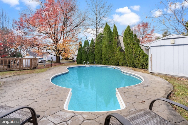 view of swimming pool featuring a storage unit, a patio, and a wooden deck