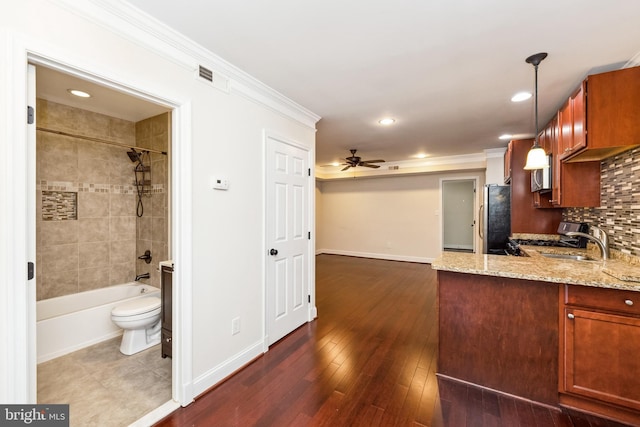 kitchen with pendant lighting, tasteful backsplash, stainless steel fridge, crown molding, and light stone countertops