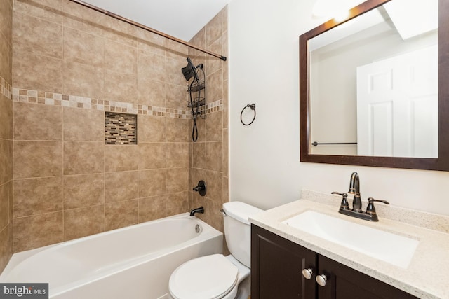 full bathroom featuring tiled shower / bath, vanity, and toilet