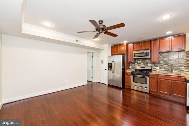 kitchen with sink, stainless steel appliances, dark hardwood / wood-style floors, light stone counters, and decorative backsplash