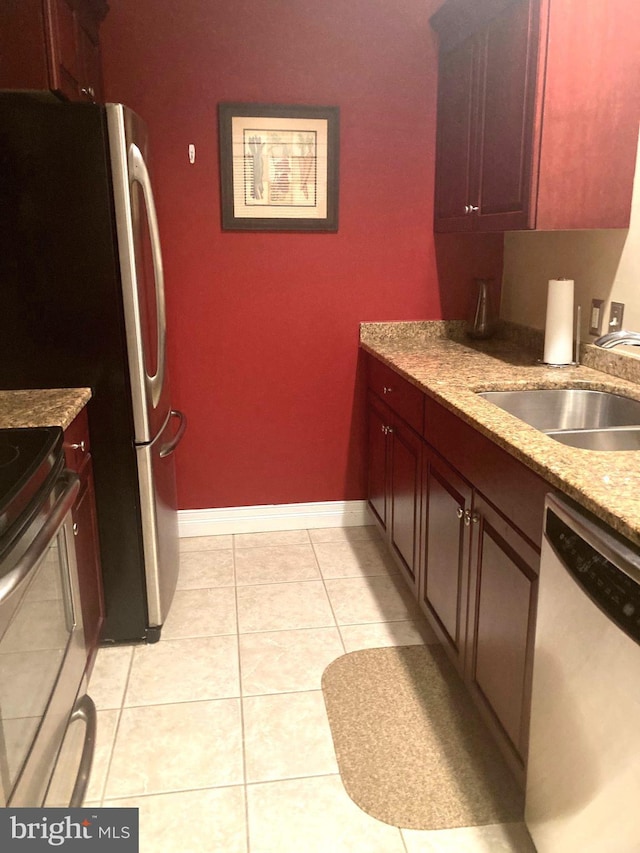 kitchen featuring light tile patterned floors, baseboards, electric range, a sink, and dishwasher