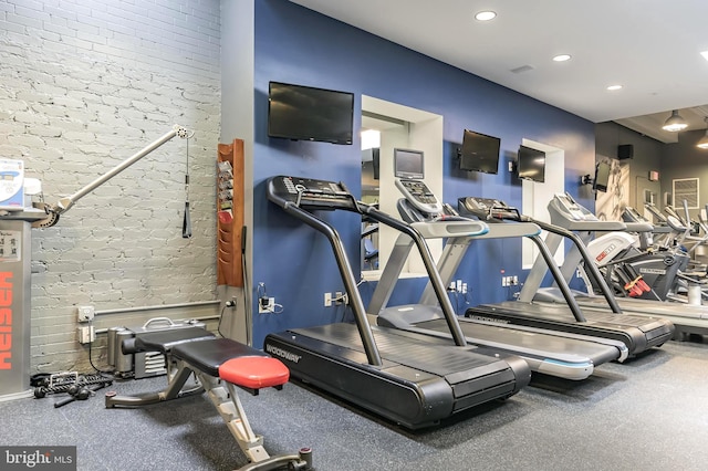 exercise room with recessed lighting and brick wall