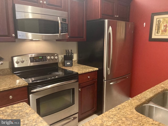 kitchen featuring light stone countertops, appliances with stainless steel finishes, and sink