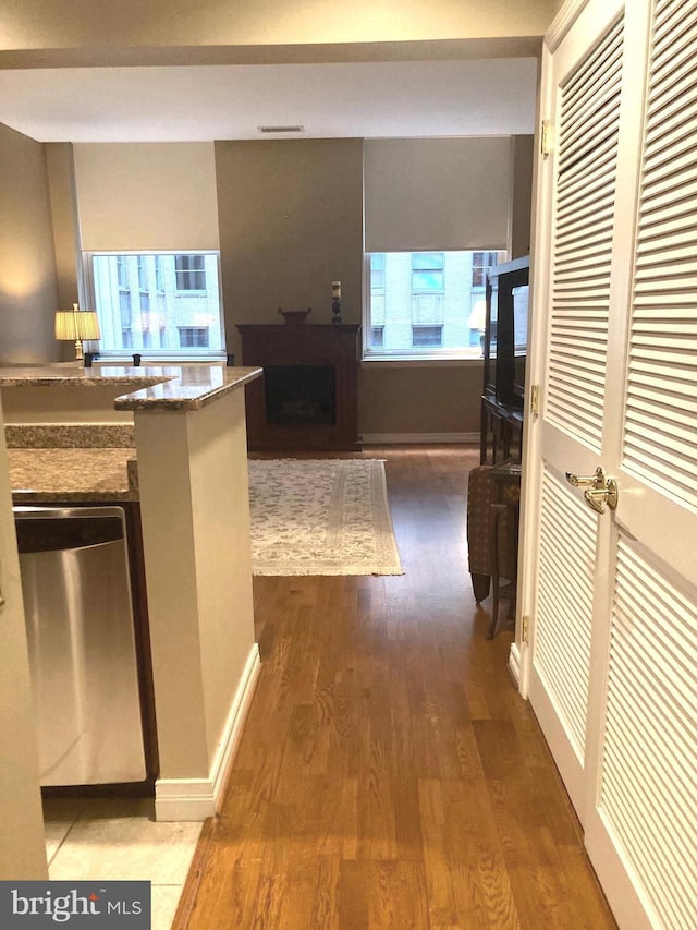 kitchen with hardwood / wood-style flooring, dark stone counters, and dishwasher