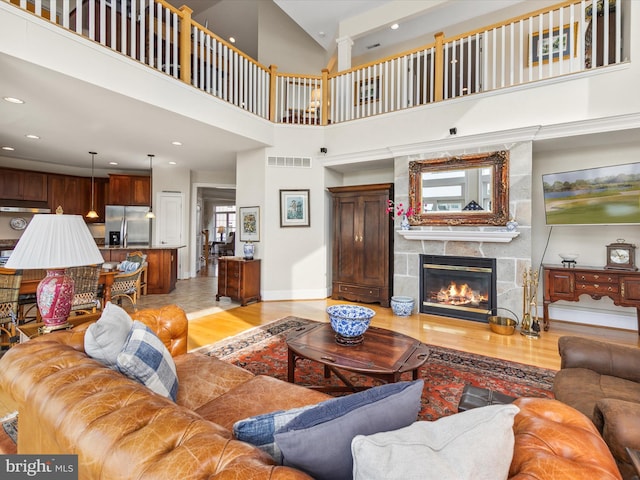 living room with a towering ceiling, a fireplace, and light hardwood / wood-style flooring