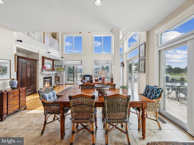 dining space featuring a towering ceiling, a tile fireplace, and light tile patterned floors