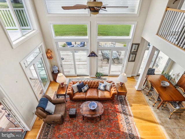 living room featuring a high ceiling, ceiling fan, and light hardwood / wood-style floors