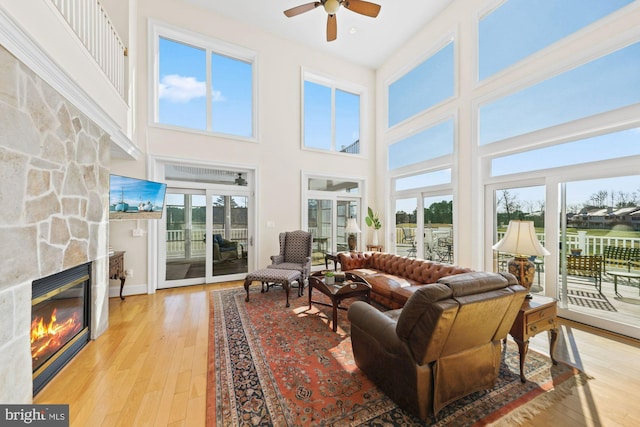 living room with ceiling fan, a fireplace, light hardwood / wood-style flooring, and a wealth of natural light