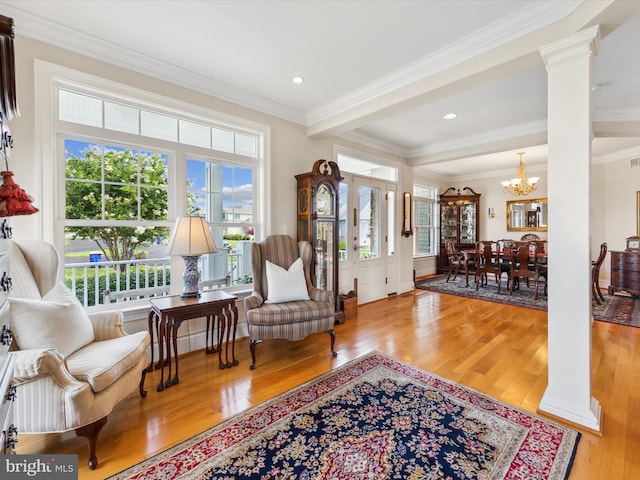 living area with a healthy amount of sunlight, ornamental molding, light hardwood / wood-style floors, and ornate columns