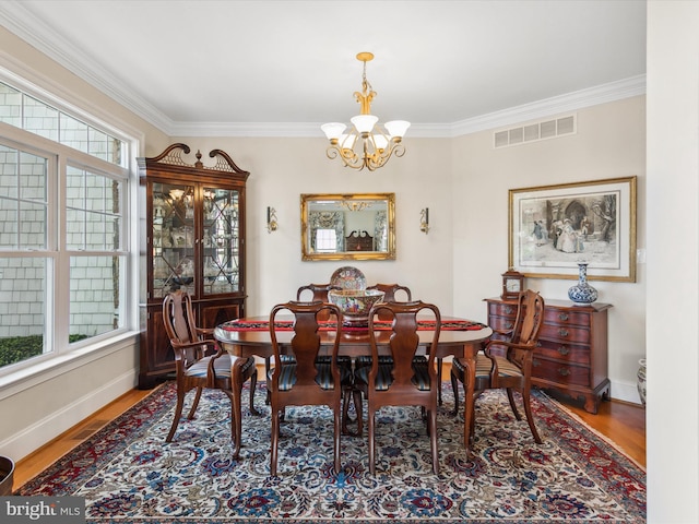 dining area with an inviting chandelier, hardwood / wood-style flooring, and ornamental molding