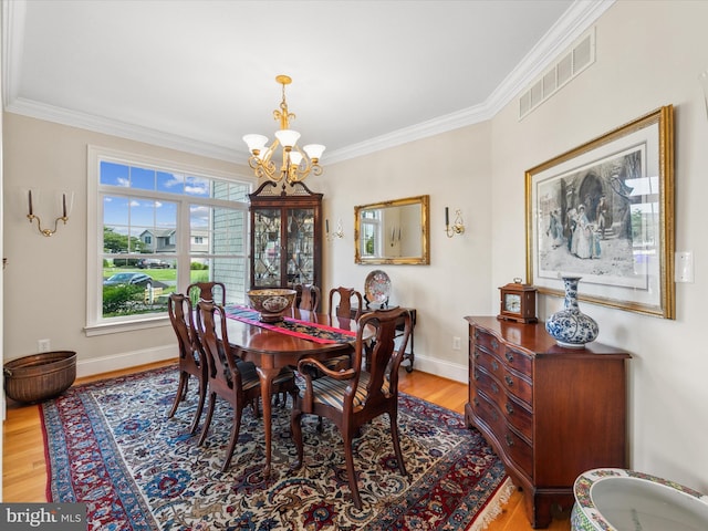 dining area with an inviting chandelier, crown molding, and light wood-type flooring