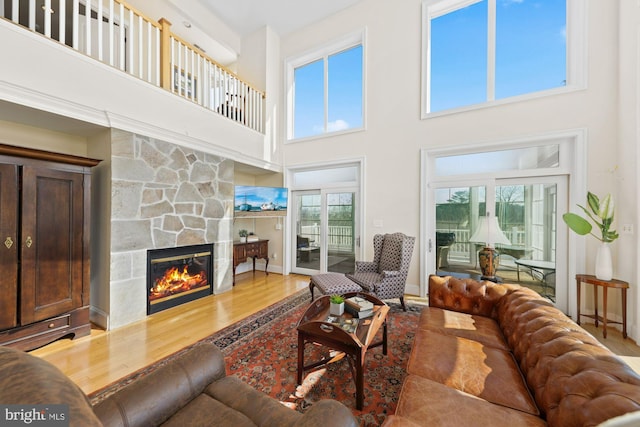 living room featuring a high ceiling, a fireplace, and wood-type flooring