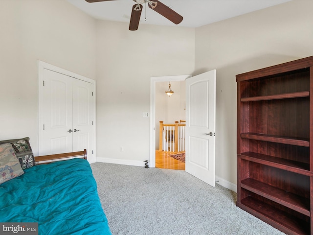 bedroom with ceiling fan, carpet flooring, and a towering ceiling