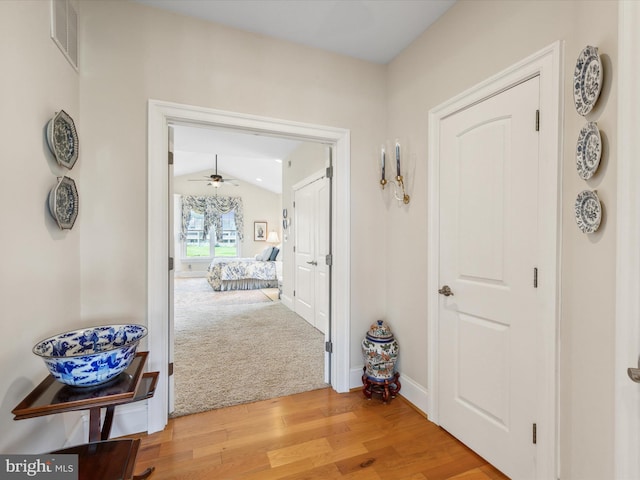 hallway with lofted ceiling and light wood-type flooring