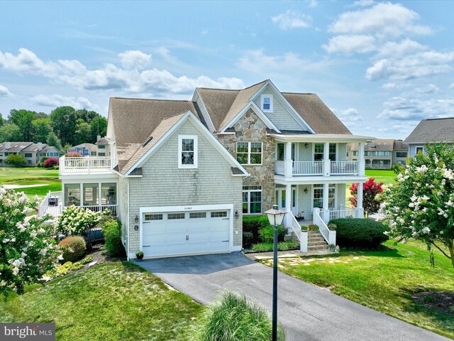 view of front facade with a garage, a balcony, a porch, and a front yard