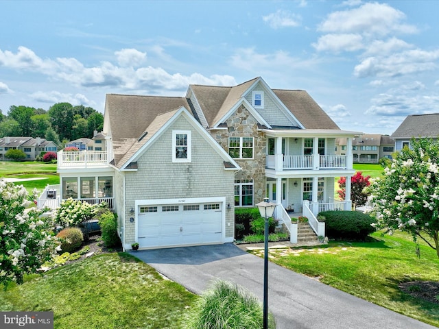 view of front of house featuring a garage, a balcony, a front yard, and covered porch