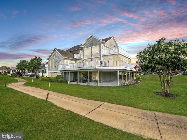 view of front of house with a wooden deck, a balcony, and a lawn