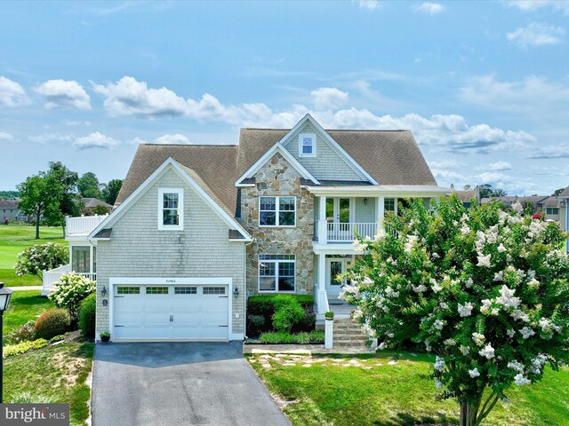 view of front of property with a garage, a balcony, and a front lawn