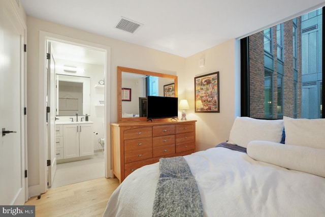 bedroom with sink, ensuite bath, and light hardwood / wood-style floors