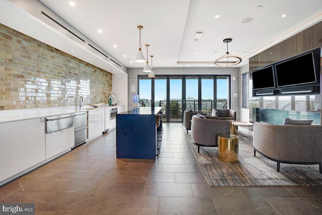 kitchen featuring hanging light fixtures, a kitchen island, sink, and white cabinets