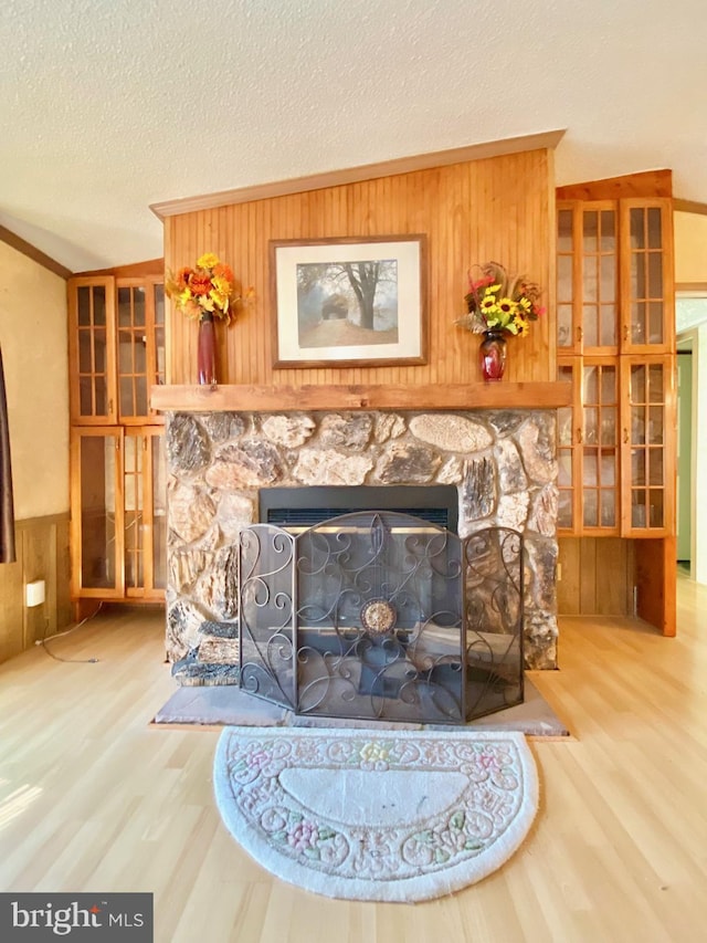 room details featuring wooden walls, hardwood / wood-style floors, a stone fireplace, and a textured ceiling