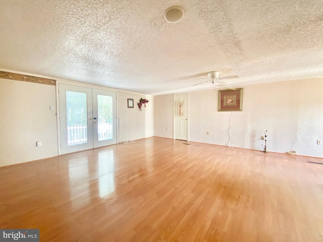 spare room featuring french doors, ceiling fan, wood-type flooring, and a textured ceiling