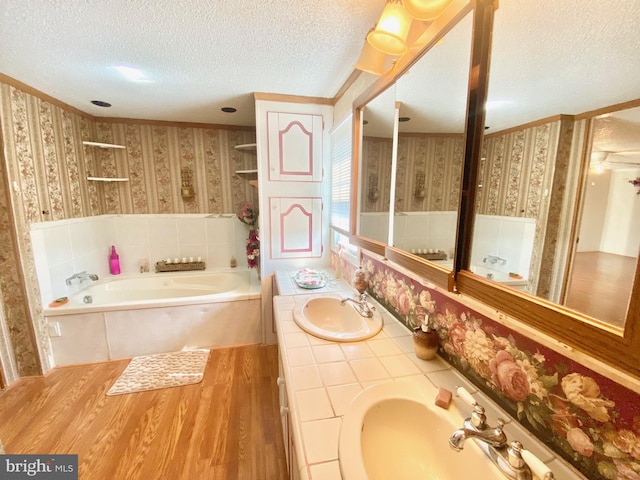 bathroom with hardwood / wood-style flooring, a tub to relax in, a textured ceiling, and vanity