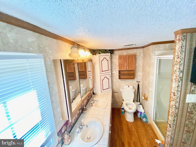 bathroom featuring a shower with door, hardwood / wood-style floors, a textured ceiling, and toilet