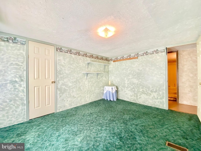 spare room with a textured ceiling and carpet flooring