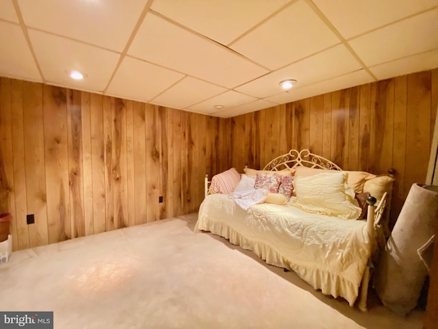 bedroom with a paneled ceiling and wood walls