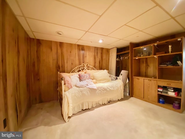 bedroom with a drop ceiling and wood walls