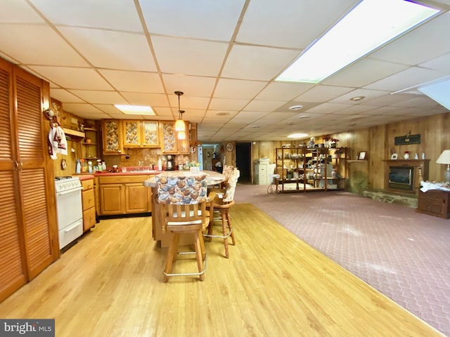 kitchen with pendant lighting, gas range gas stove, a kitchen bar, a drop ceiling, and light carpet