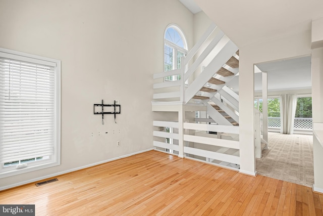 interior space with light hardwood / wood-style floors, a healthy amount of sunlight, and a high ceiling