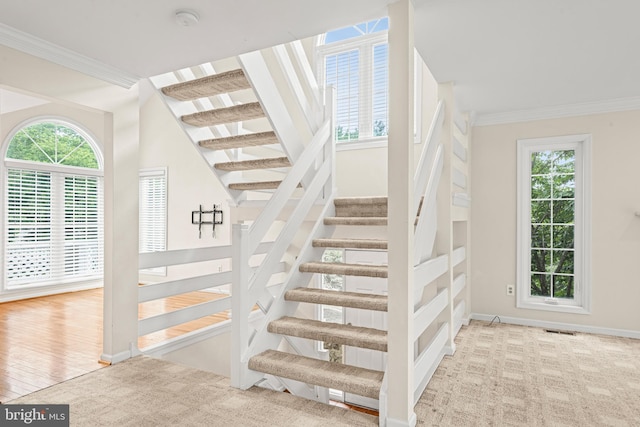 stairs with ornamental molding and light hardwood / wood-style floors