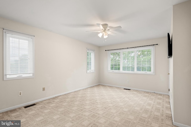 empty room featuring a healthy amount of sunlight, light colored carpet, and ceiling fan